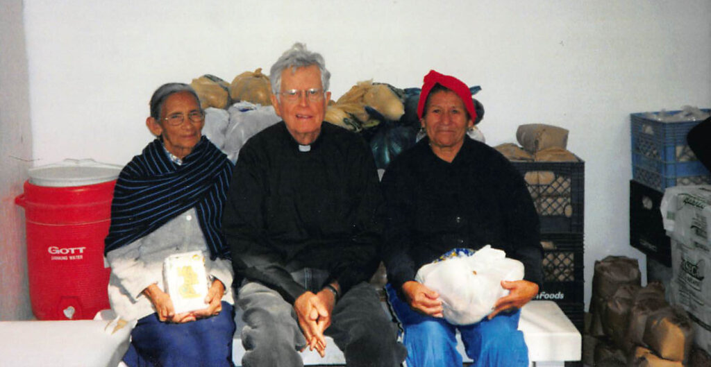 Father Rick Thomas with two women from Food Bank